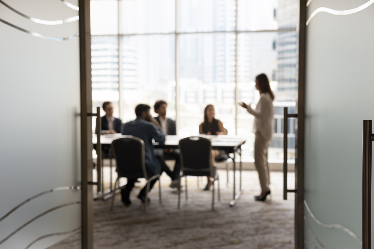 Silhouettes of businesspeople gathered in conference room, blurred view