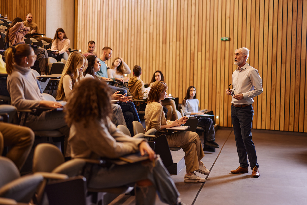 Mature professor talking on a class at lecture hall.